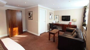 A living room with a sofa, a coffee table, a TV, a desk, and a wardrobe. - Dolphin Sa1 (Swansea)