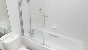 A modern bathroom with a glass-enclosed shower, a white toilet, and a bathtub with a towel. - Dolphin Sa1 (Swansea)