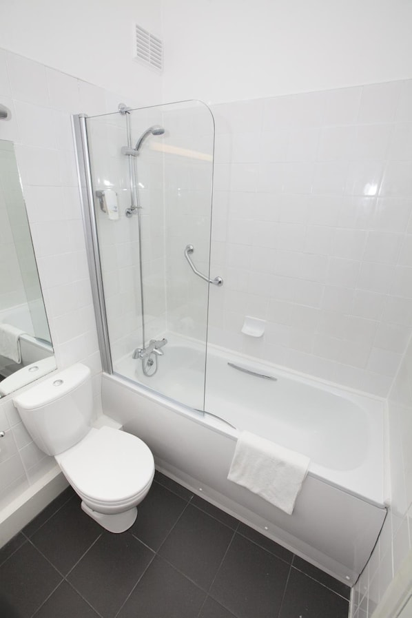 A modern bathroom with a glass-enclosed shower, a white toilet, and a bathtub with a towel.
