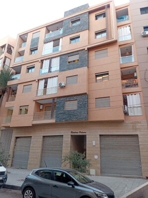 A multi-story residential building with balconies, air conditioning units, and a garage entrance. - Modern studio in the heart of Guéliz (Marrakech)