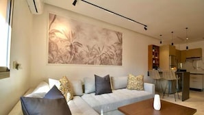 Ein modernes Wohnzimmer mit einer Couch, einem Couchtisch und einer Küche im Hintergrund.