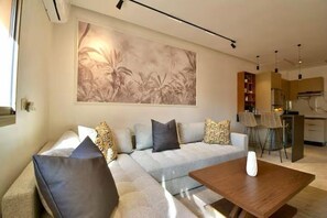 Ein modernes Wohnzimmer mit einer Couch, einem Couchtisch und einer Küche im Hintergrund.