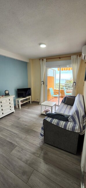 Ein Wohnzimmer mit Sofa, Fernseher und einem Balkon mit Blick.