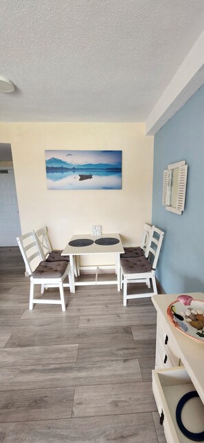 Ein Essbereich mit Tisch und Stühlen, einem Bild an der Wand und einem Spiegel.