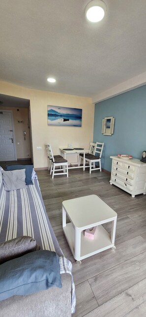 Ein Wohnzimmer mit einer Couch, einem Esstisch mit Stühlen, einem kleinen weißen Tisch und einer Kommode.