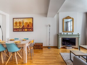 A dining area with a table set for four, a fireplace, and a large mirror above it.