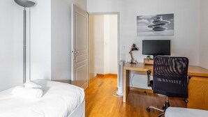 A hotel room with a bed, desk, chair, TV, and artwork on the wall. - L'Heure Dorée - Duplex under the Grosse Horloge (La Rochelle)
