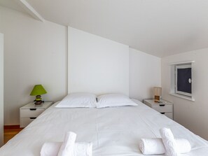 A minimalist hotel room with a large bed, two bedside tables, and a window.
