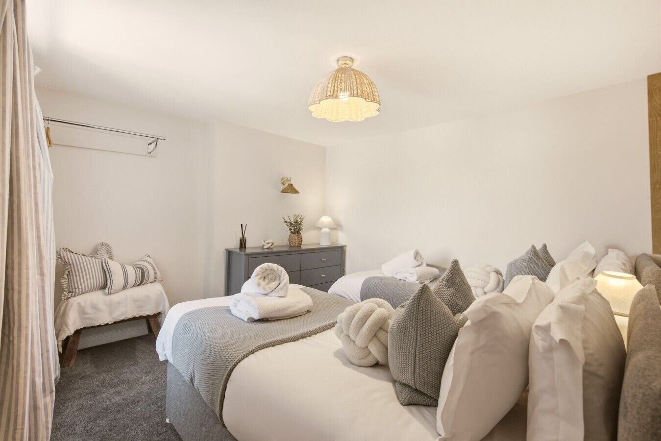 A bedroom with a bed, bedside tables, a hanging light fixture, and a wardrobe.
