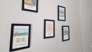 Eine Wand mit fünf gerahmten Kunstwerken, die Küstenlandschaften zeigen.