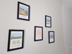 Eine Wand mit fünf gerahmten Kunstwerken, die Küstenlandschaften zeigen.