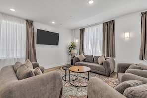 Ein modernes Wohnzimmer mit einer Sofagarnitur, einem Couchtisch und einem an der Wand befestigten Fernseher.