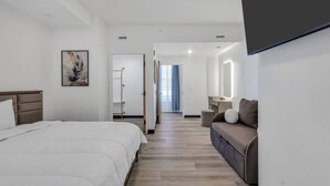 Ein Hotelzimmer mit Bett, Sofa, Schreibtisch und Spiegel.