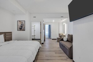 Ein Hotelzimmer mit Bett, Sofa, Schreibtisch und Spiegel.