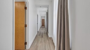 Ein Flur mit Holzt üren, einem hellen Boden und Blick in einen Raum am Ende.