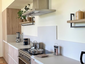 A modern kitchen with a built-in oven, a coffee maker, and a kettle on the counter.