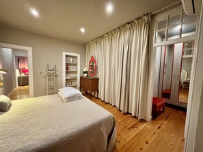 Ein Schlafzimmer mit Bett, Kommode, Spiegel und Kleiderschrank.