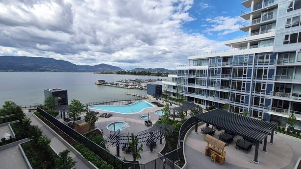A modern hotel with a pool area, outdoor seating, and a view of the lake. - Kelowna Aqua Waterfront Rental (Kelowna)