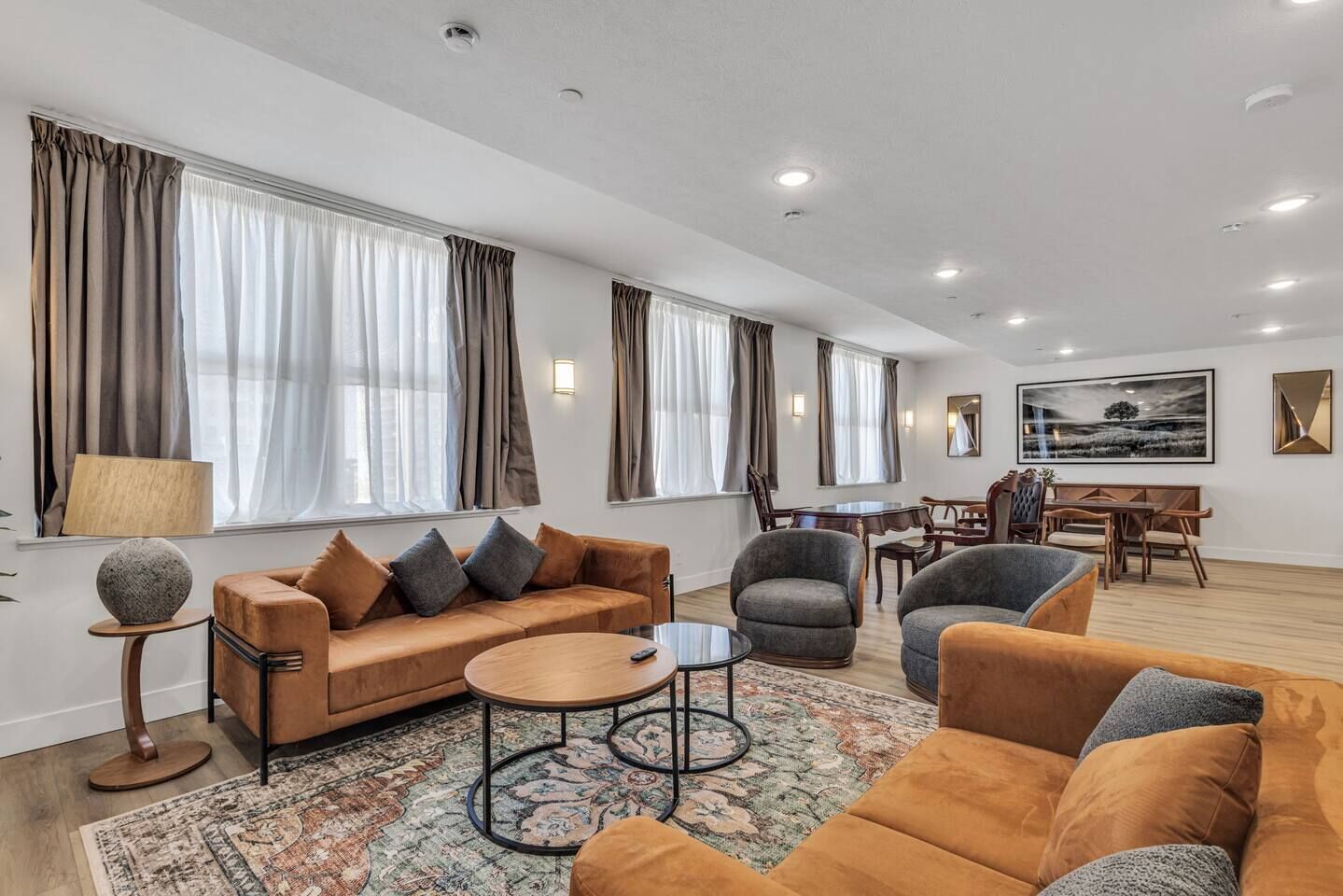 A spacious living room with a sofa, armchairs, a coffee table, and a dining area with chairs and a table.