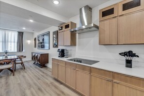 A modern kitchen with wooden cabinets, a stainless steel range hood, and a built-in stove. - Downtown Indy Grand Flat 2,800 Sqft- Flat 9 (Indianapolis)