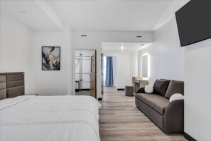 Ein Hotelzimmer mit einem Bett, einer Couch, einem Spiegel und einer Tür zu einem Badezimmer.