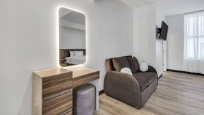 Et moderne værelse med et træbord, en sofa, et fjernsyn og et stort spejl.