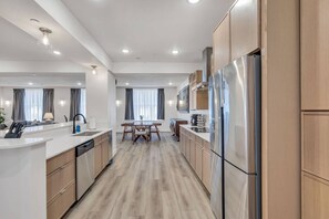 Eine moderne Küche mit Holzschränken, Edelstahlgeräten und einer zentralen Kochinsel mit Sitzgelegenheit.