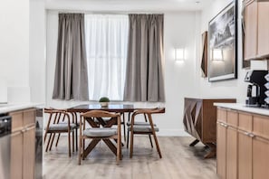 Eine moderne Küche mit Holzausstattung, einem Esstisch mit Stühlen und einem Fenster mit Vorhängen.