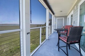 A covered outdoor area with a table and chairs, a view of the landscape, and a door. - Sunset Corner ~ Surrounding river views (Folly Beach)