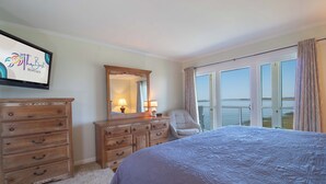 Una camera da letto con un letto, una cassettiera, uno specchio e vista sull'oceano.
