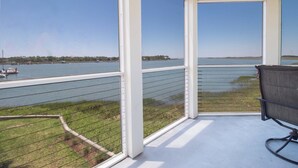 Un balcone con vista su uno specchio d'acqua, una sedia e una ringhiera.
