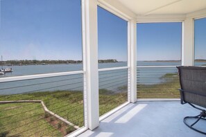 A balcony with a view of a body of water, a chair, and a railing. - Sunset Corner ~ Surrounding river views (Folly Beach)