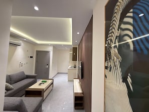 A modern living room with a sofa, coffee table, and a painting on the wall. - 103 JRE Comfortable and Accessible Retreat (Amman)
