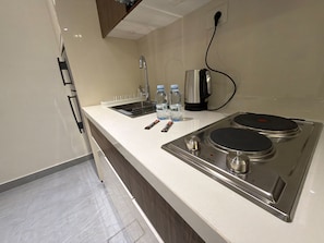 Una kitchenette con estufa de acero inoxidable, un lavamanos y dos botellas de agua.