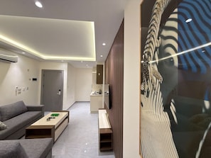 A modern living room with a sofa, coffee table, and a painting. - 103 JRE Comfortable and Accessible Retreat (Amman)