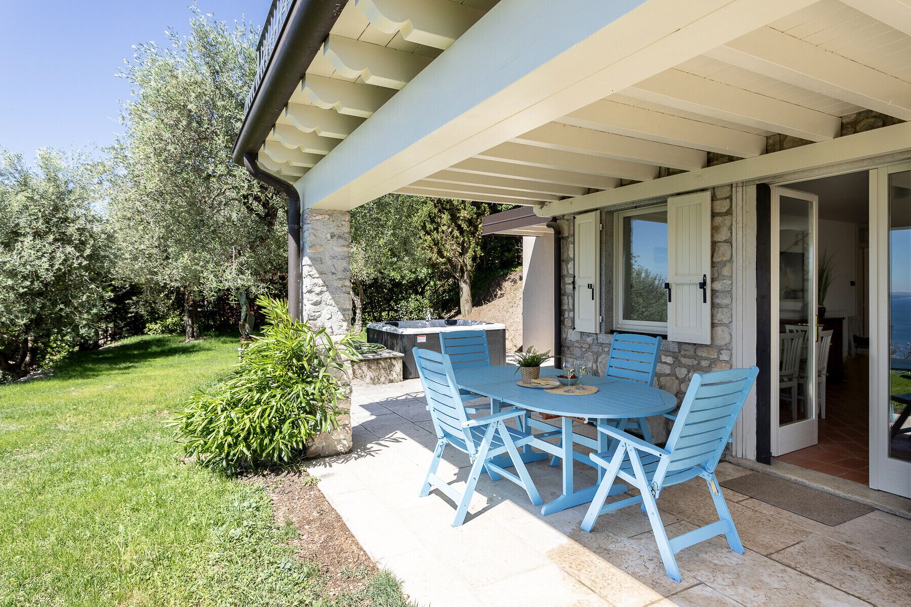 An outdoor patio with a table and chairs, a stone wall, and a view of the sea.