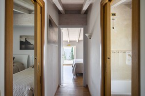 Ein Flur, der zu einem Schlafzimmer mit Bett, einem Badezimmer mit Badewanne und einem Balkon mit Blick führt.