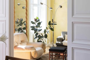 A room with a sofa, a chair, a floor lamp, and potted plants. - Magnificent Copenhagen home with artistic charm (Frederiksberg)