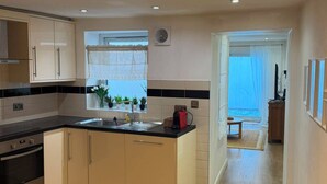 A modern kitchen with a central island, built-in oven, and a dining area with a wooden table and chairs. - Enjoyable 3-bedroom apartment in charming Hampton Wick neighborhood (Hampton Wick)
