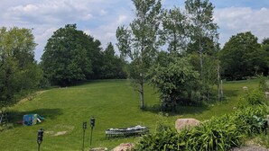 En græsplæne med træer, en legeplads og et picnicbord.