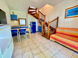 Um espaço compacto com cozinha compacta, área de refeições, sofá e escada de madeira.