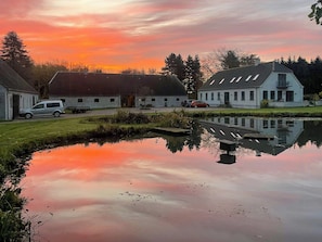 Eine friedliche Seenlandschaft mit einem Haus, einem geparkten Auto und einem kleinen Steg.
