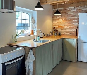 Eine Küche mit Herd, Spüle und Kühlschrank, mit einer Ziegelwand und Holzbalkendecke.