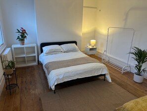 A neatly arranged bedroom with a bed, bedside tables, a radiator, and a window. - Charming Victorian Townhouse & Garden (London)
