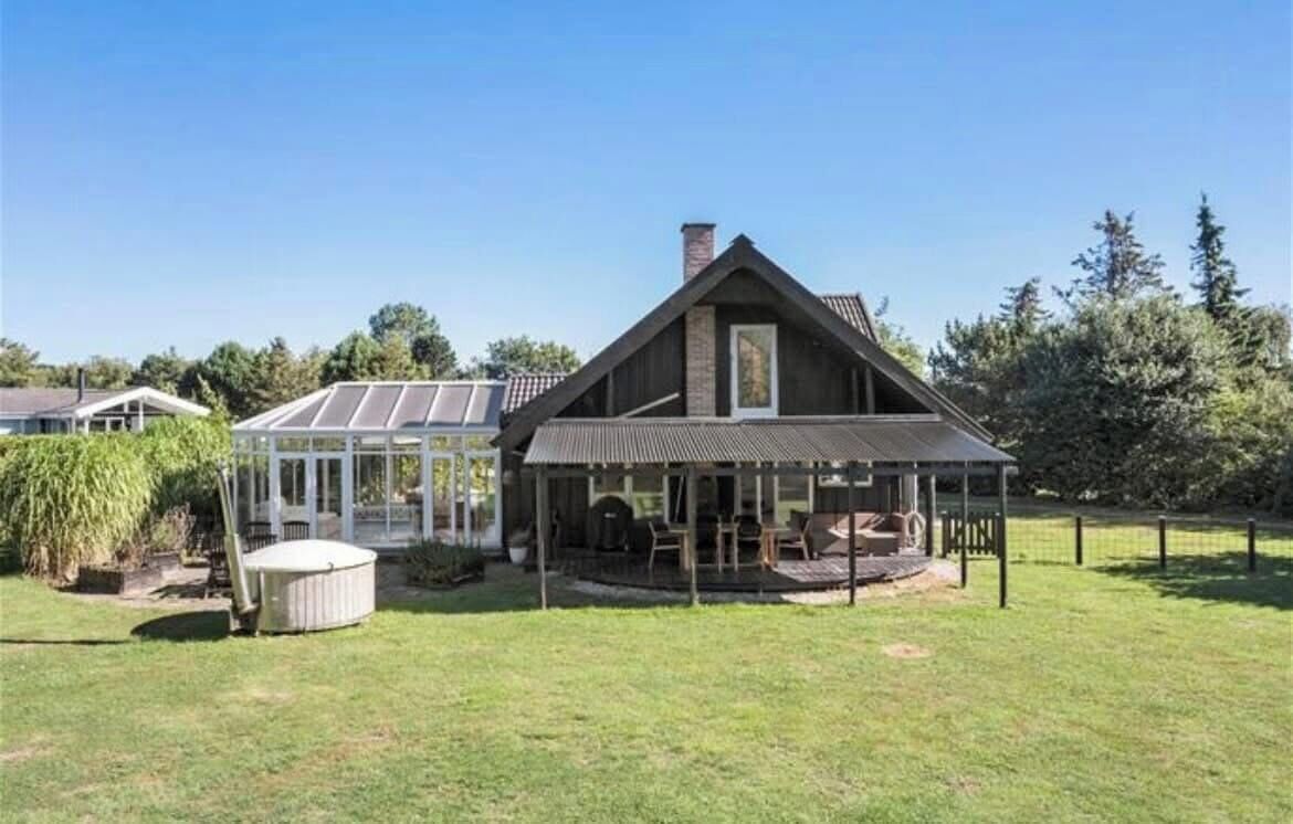 Une maison dotée d’une grande terrasse, d’une véranda et d’une cheminée.