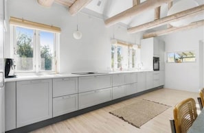 Eine moderne Küche mit einer langen Arbeitsplatte, weißen Schränken und Holzbalken an der Decke.