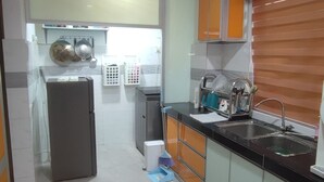 Eine Küche mit Kühlschrank, Spüle und orangenen Schränken.