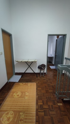 A room with a wooden parquet floor, a small folding table, a chair, and a crib.