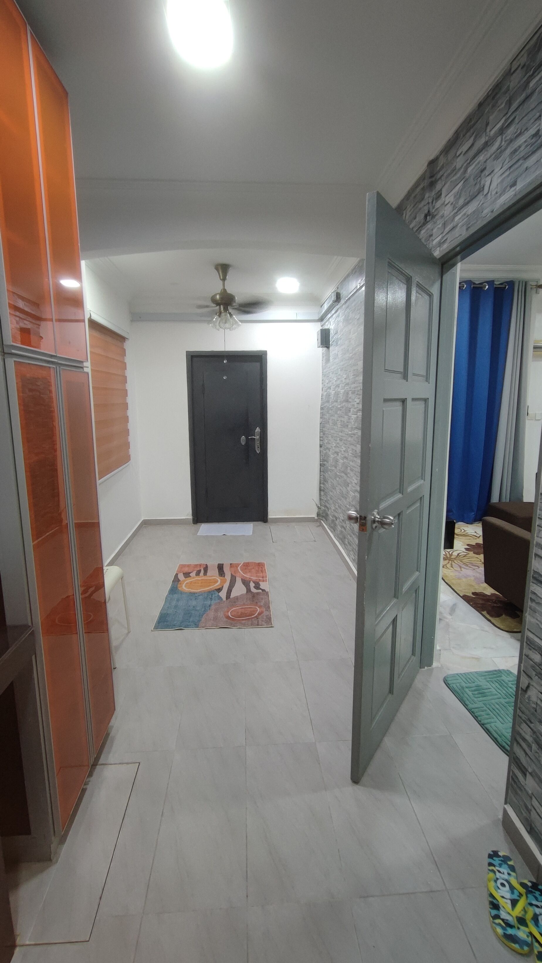 A hallway with a ceiling fan, a black door, and a patterned rug on the floor.