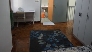 Ein Schlafzimmer mit Bett, Schreibtisch, Stuhl, Kleiderschrank und einem durch eine offene Tür erreichbaren Badezimmer.